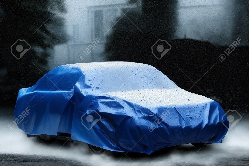 Zaparkowany samochód z pokrywą ochronną w deszczu