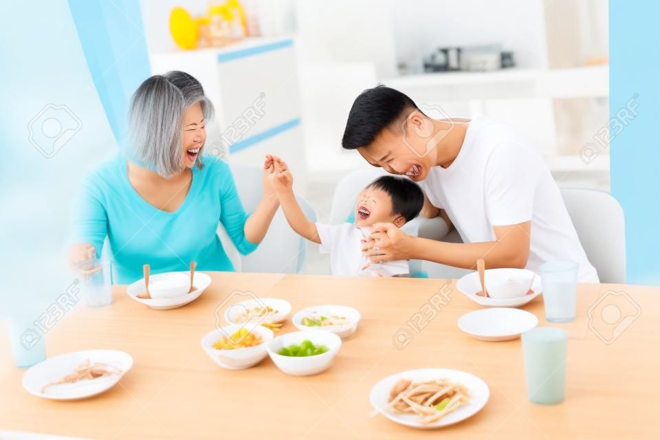 Szczęśliwa azjatycka rodzina ojca, matki i syna, grając i śmiejąc się podczas obiadu