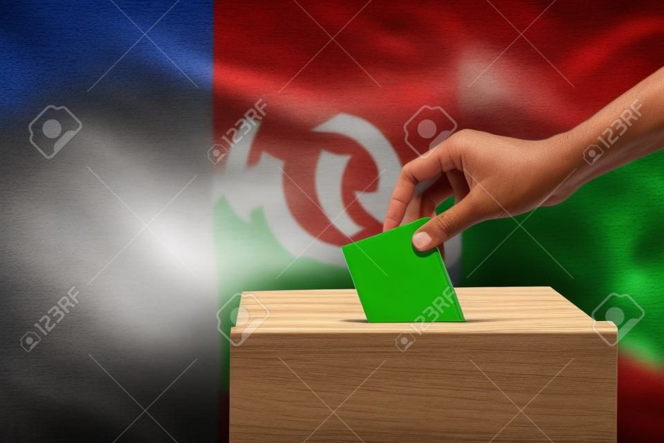 Close-up do elenco de mão humana e inserir um voto e escolher e tomar uma decisão o que ele quer na caixa de votação com a bandeira do México misturado em segundo plano
