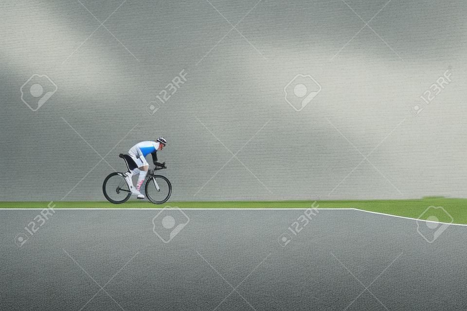 Ciclista bello in abbigliamento sportivo in bicicletta su strada