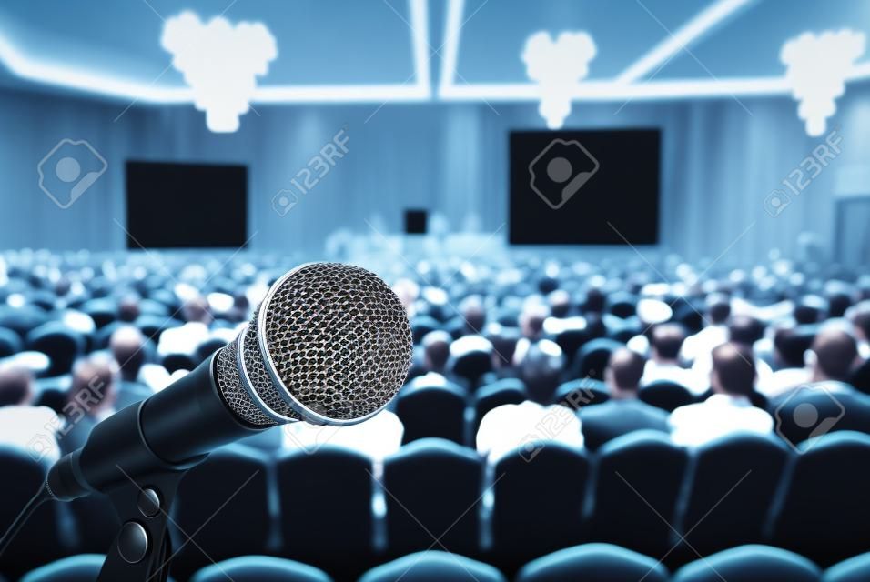 Microfone sobre a foto borrada abstrata da sala de conferências ou sala de seminários com fundo do participante, conceito de reunião de negócios