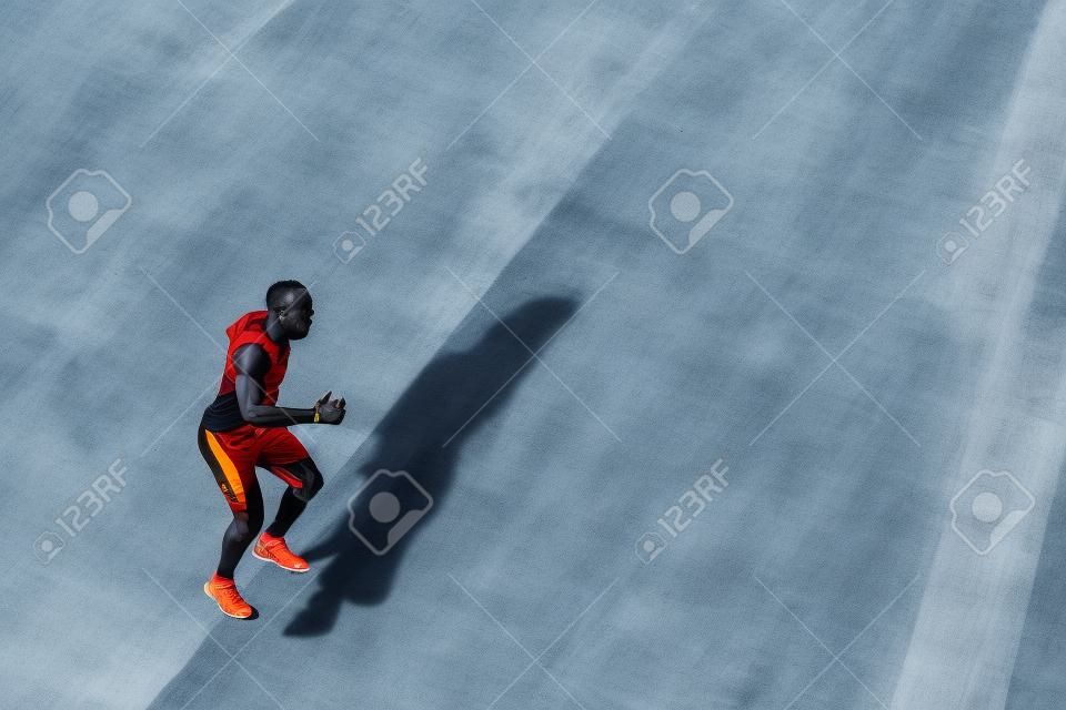 African black sportsman running upwards with energy on the stadium bleachers