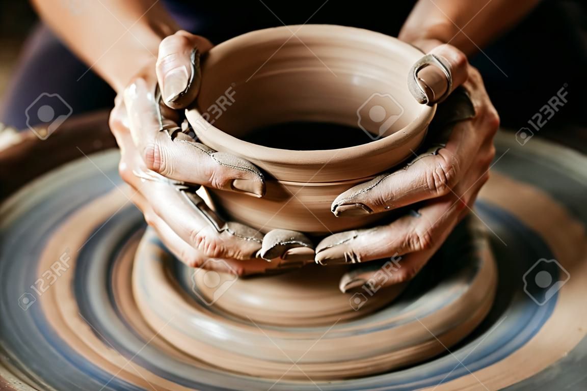 工作在投擲的輪子的女性陶瓷工在演播室。黏土車間