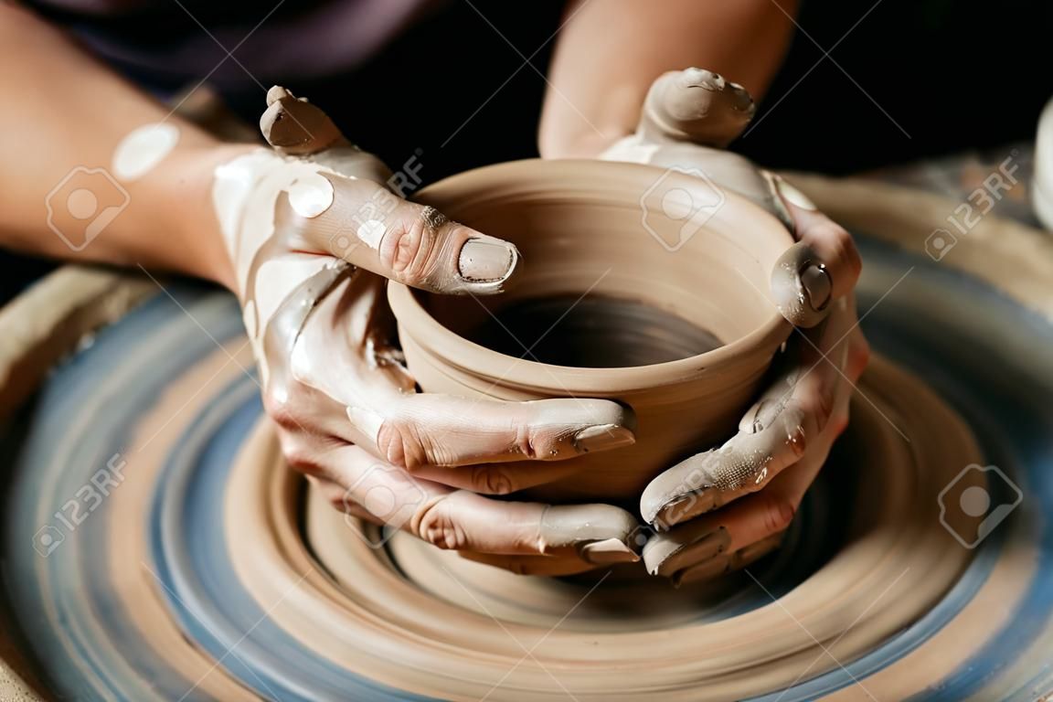 Female potter working at throwing wheel at studio. Clay workshop