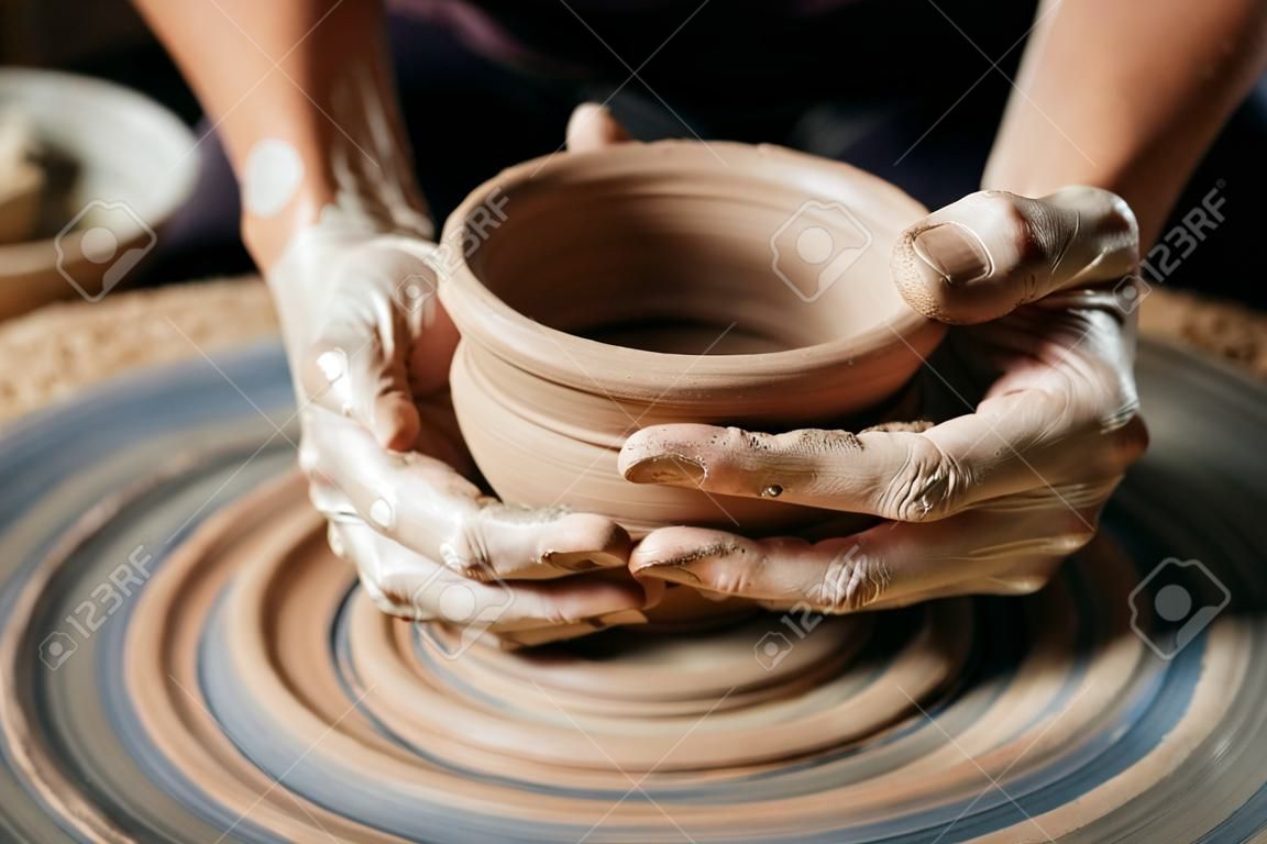 Female potter working at throwing wheel at studio. Clay workshop