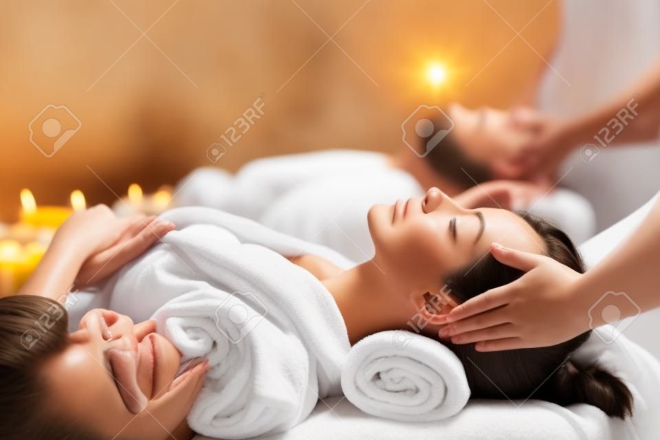 heureux jeune beau couple profitant d'un massage de la tête au spa