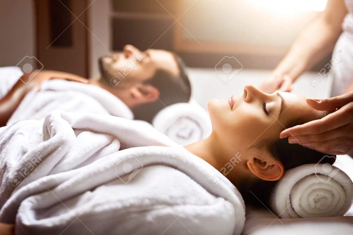 счастливая молодая красивая пара наслаждается массажем головы в спа-салоне