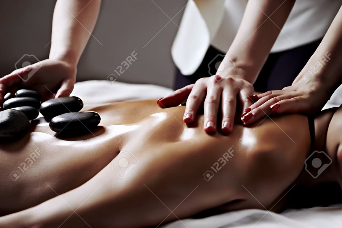 Kobieta podczas masażu gorącymi kamieniami w koncepcji zabiegów kosmetycznych w salonie spa