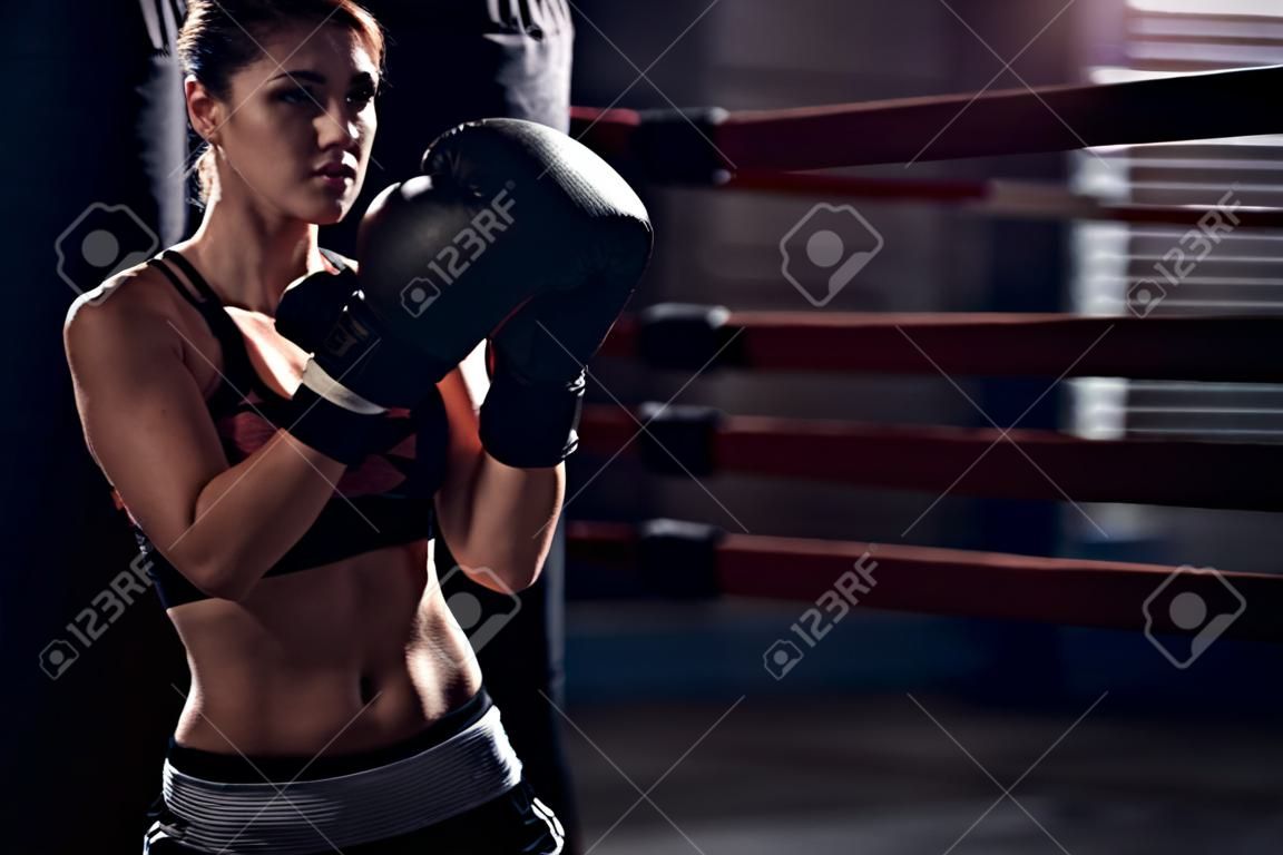 Female Boxer wearing gloves posing in boxing studio