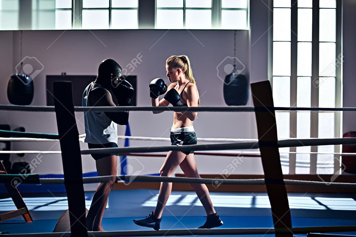 Frau, die mit Trainer an der Boxe- und Selbstverteidigungslektion trainiert. Kopieren Sie Platz