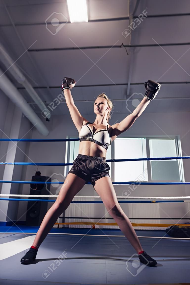 lage hoek uitzicht van vrouw bokser vieren overwinning terwijl man liggend op ring vloer