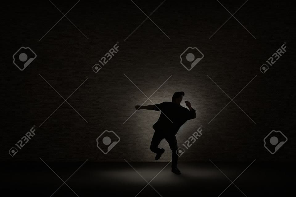dancing pose of male on one leg on the dark background