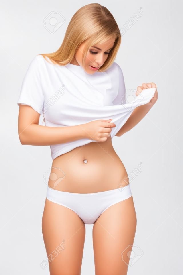 Attractive caucasian woman in white underwear demonstrates her flat belly, isolated over white background. Model of sports, dieting, fitness or plastic surgery and aesthetic cosmetology