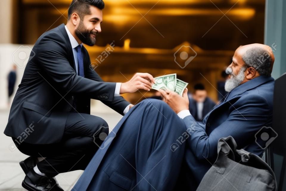 Un uomo gentile in completo accovacciato ai senzatetto e donava denaro, una banconota da un dollaro al mendicante maschio