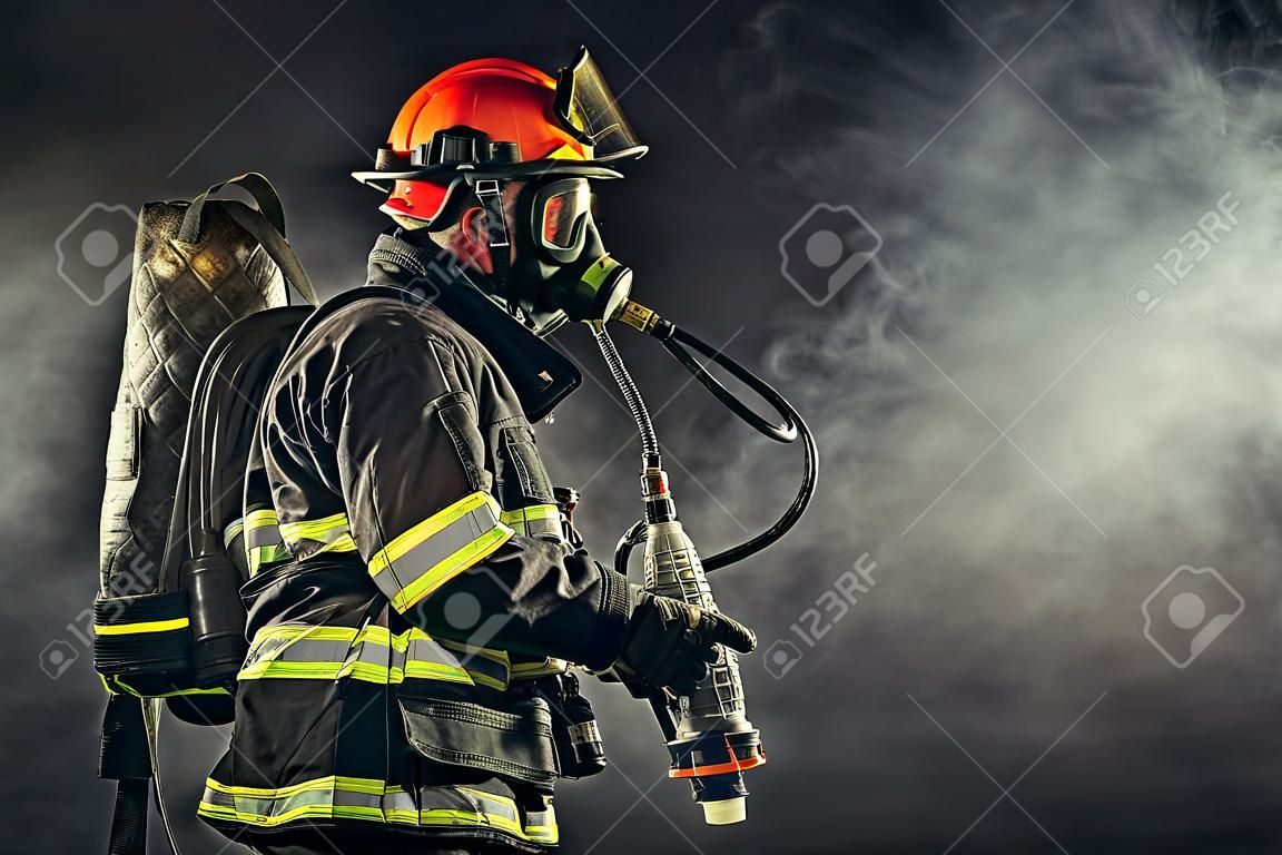 Bombeiro forte em traje de proteção e capacete usar equipamentos especiais para prevenir o fogo e salvar pessoas e animais do fogo