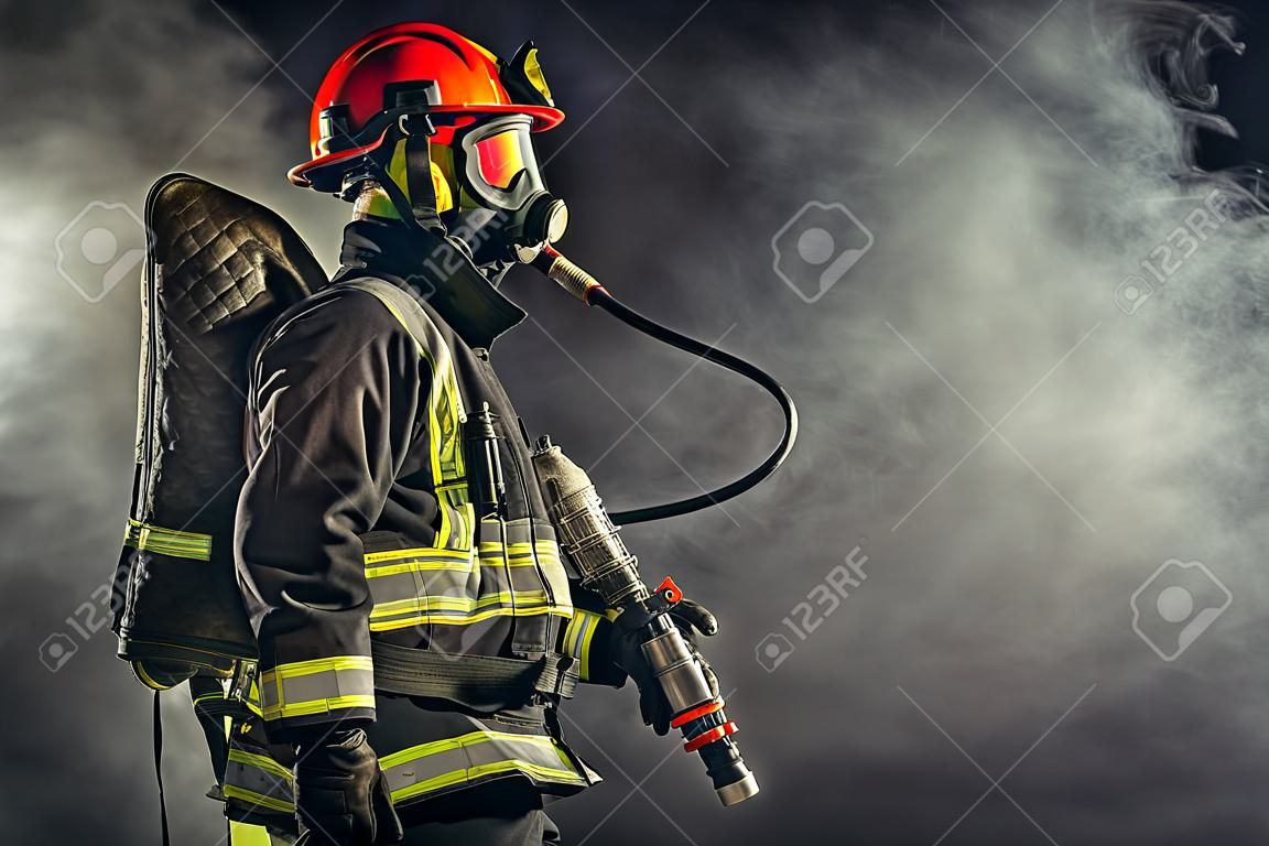 Bombeiro forte em traje de proteção e capacete usar equipamentos especiais para prevenir o fogo e salvar pessoas e animais do fogo