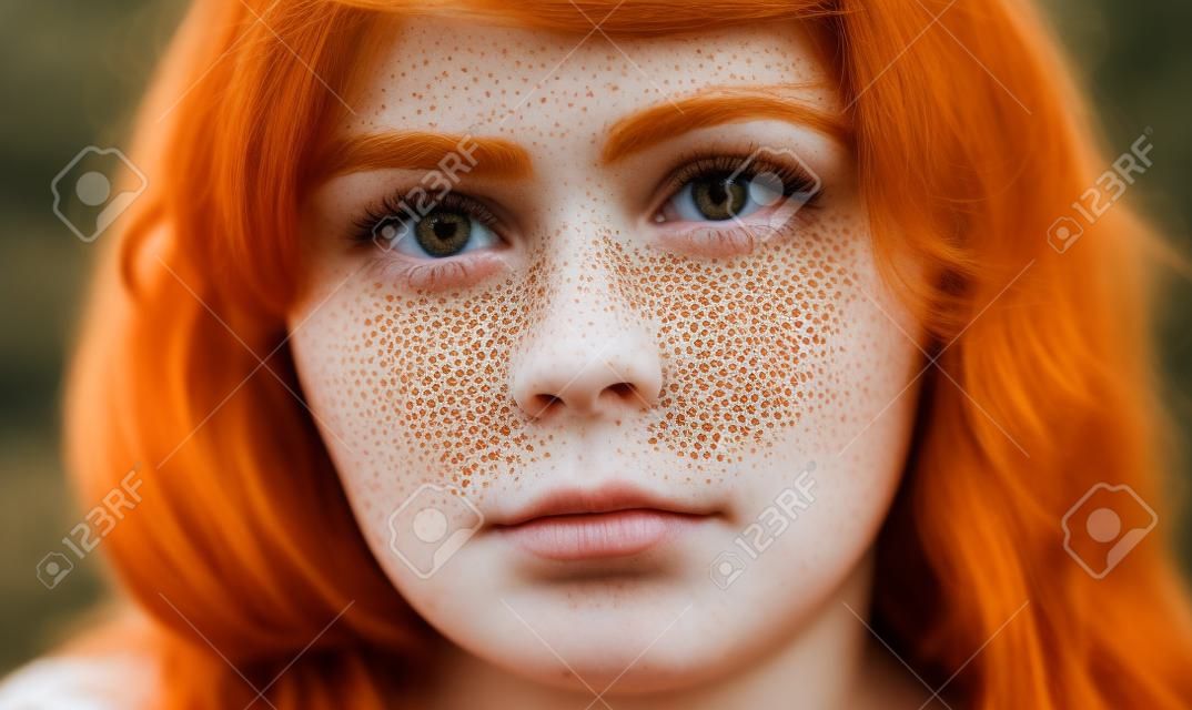 Close up shot of beautiful girl with ginger hair and freckles looking at the camera with serious expression, beauty , people, unusual beauty