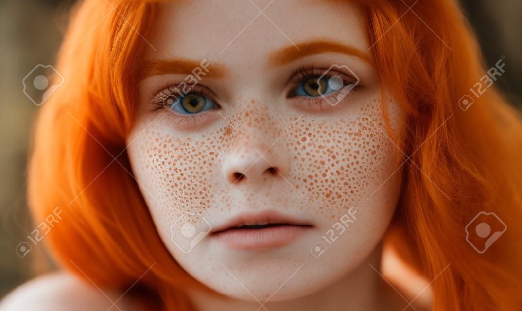 Close up shot of beautiful girl with ginger hair and freckles looking at the camera with serious expression, beauty , people, unusual beauty