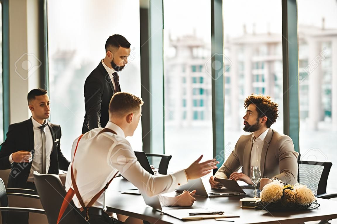 succesvolle vergadering van business crew bestond uit jonge mannen leiders in formele slijtage, verzameld om zakelijke ideeën en projecten te bespreken. geïsoleerd in het moderne kantoor