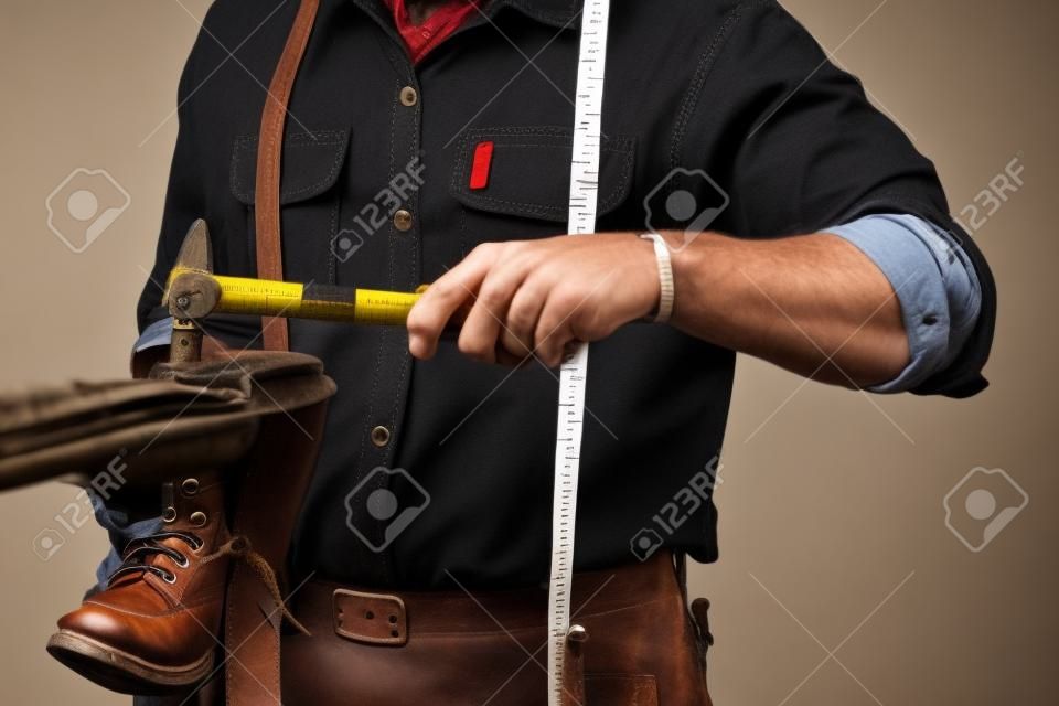 Imagen recortada de un zapatero con cinta métrica, trabajando con un zapatero que trabaja con botas de cuero usando un martillo artesanal, tiro aislado sobre fondo blanco