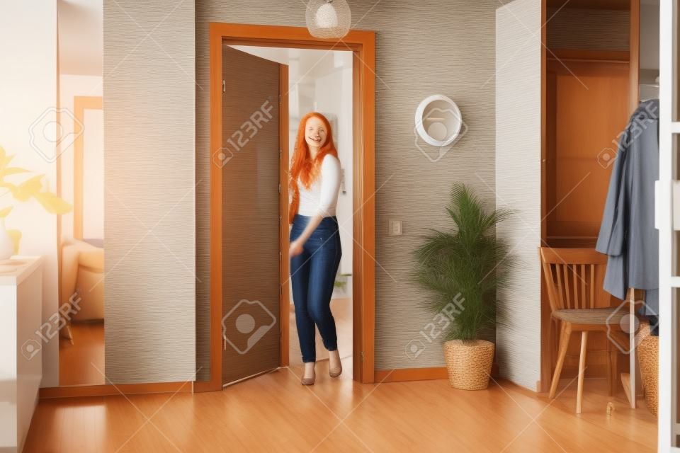 adorable redhead woman moved to new apartment, she is carrying suitcase, happy to live in new house, check the room