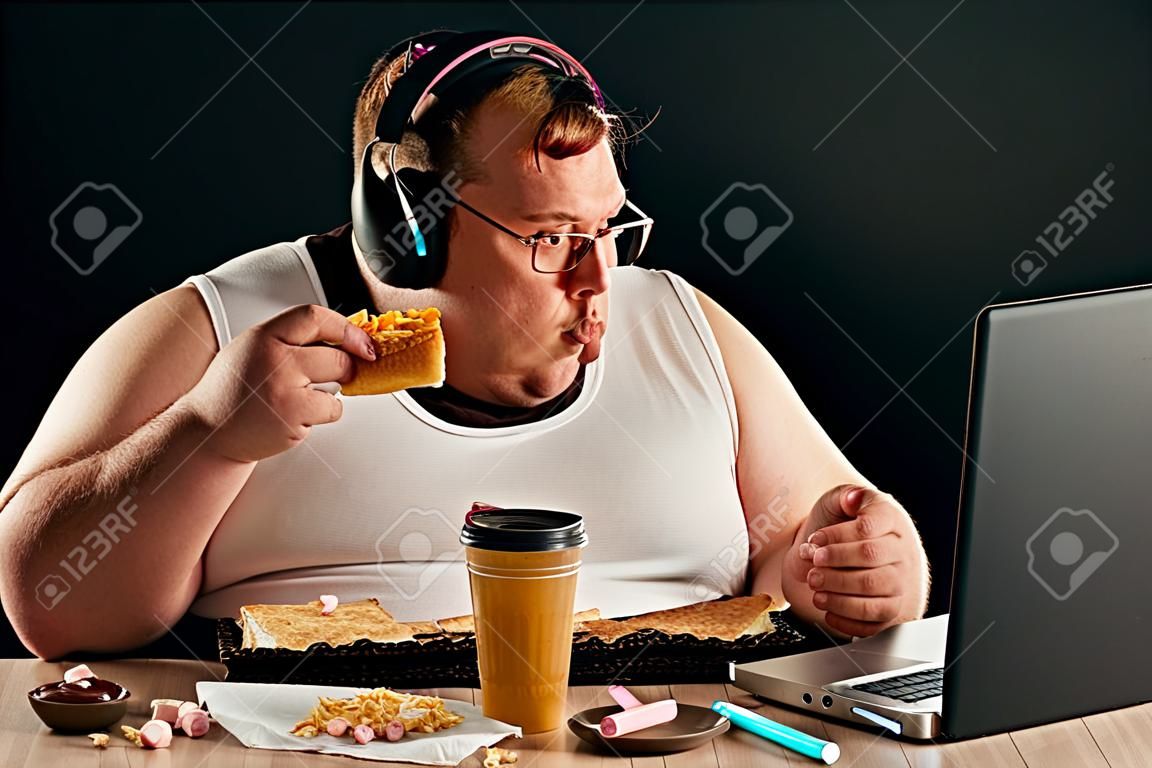 gars obèse discutant en ligne avec des amis isolés sur fond noir. portrait en gros plan. Internet, concepts de conversation