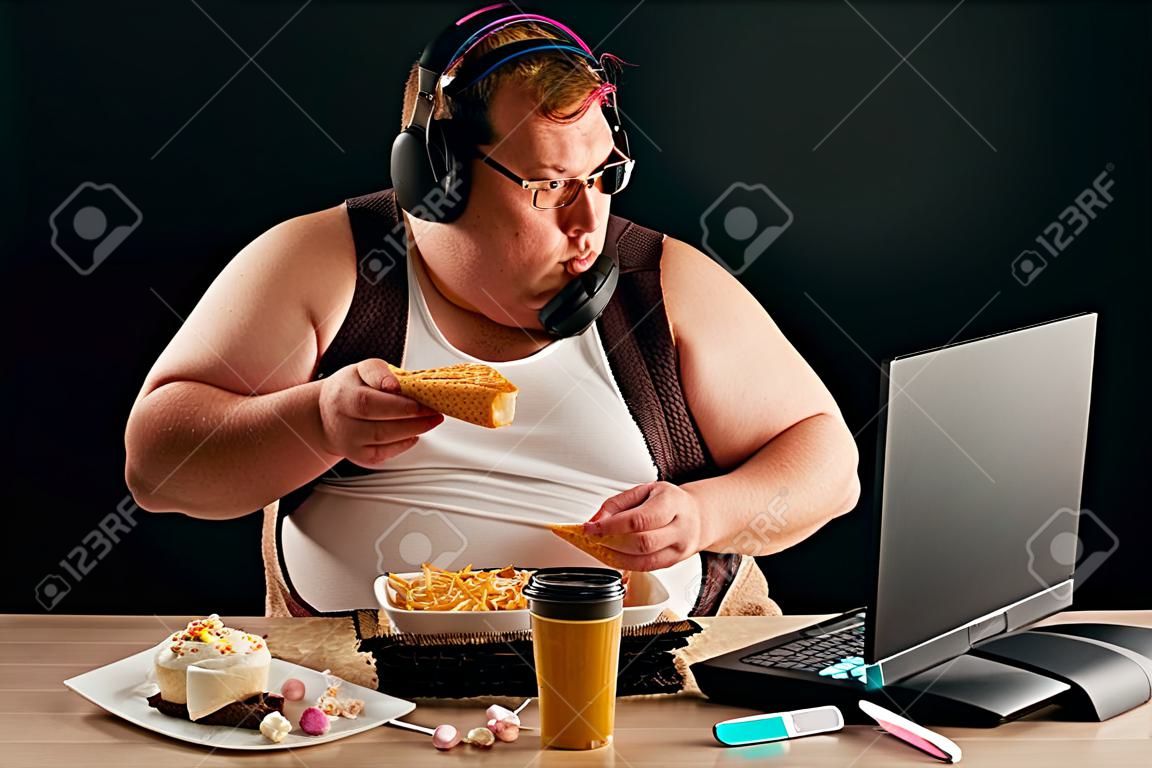gars obèse discutant en ligne avec des amis isolés sur fond noir. portrait en gros plan. Internet, concepts de conversation