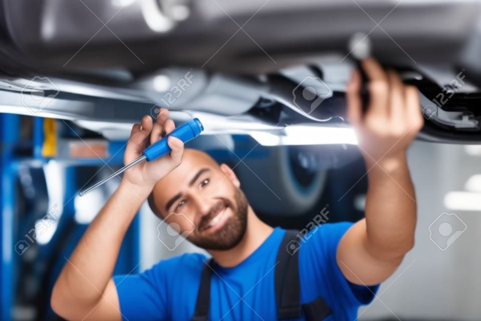 Mechanik pracuje nad pojazdem w serwisie samochodowym, sam w nowoczesnym czystym warsztacie