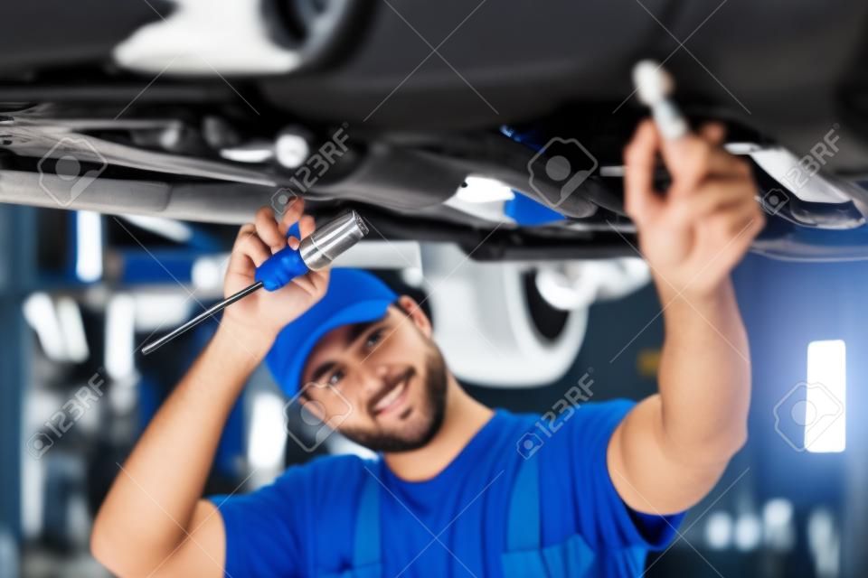 male mechanic is working on a vehicle in a car service, alone in modern clean workshop