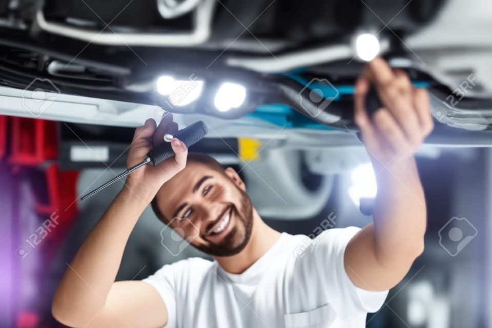 Mechanik pracuje nad pojazdem w serwisie samochodowym, sam w nowoczesnym czystym warsztacie