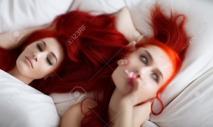 irreconhecível atraente, contente, jovem, sexy, mulher com cabelos vermelhos brilhantes tingidos relaxando na cama, esfrega os olhos quando ela acorda, copia espaço