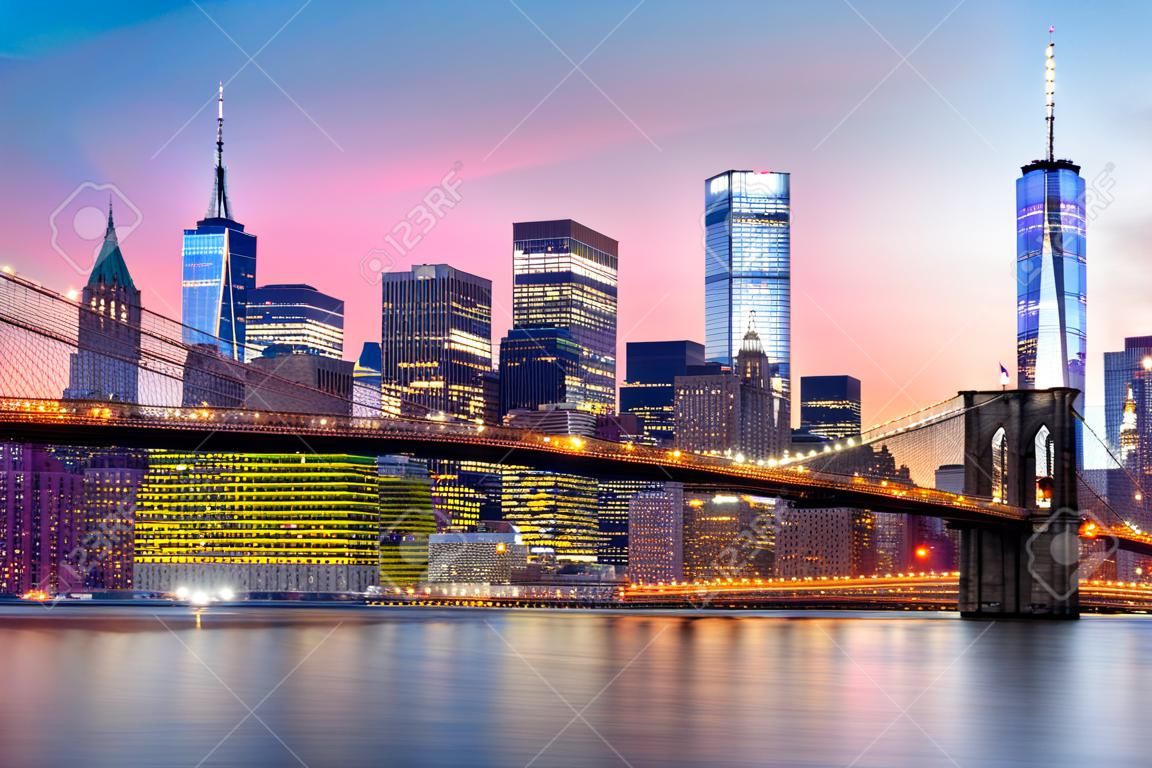 ブルックリン橋と紫の夕日の下でより低いマンハッタンのスカイライン