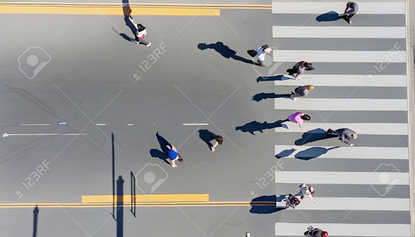 Top aerial view of group people walk at street city with pedestrian crosswalk in transport traffic road with sunlight and shadow silhouette