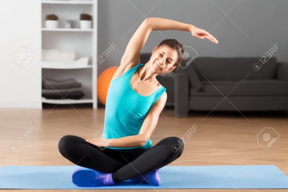 Fit donna si estende la schiena esercizio di colonna vertebrale riscaldi ginnastica aerobica concetto a casa.