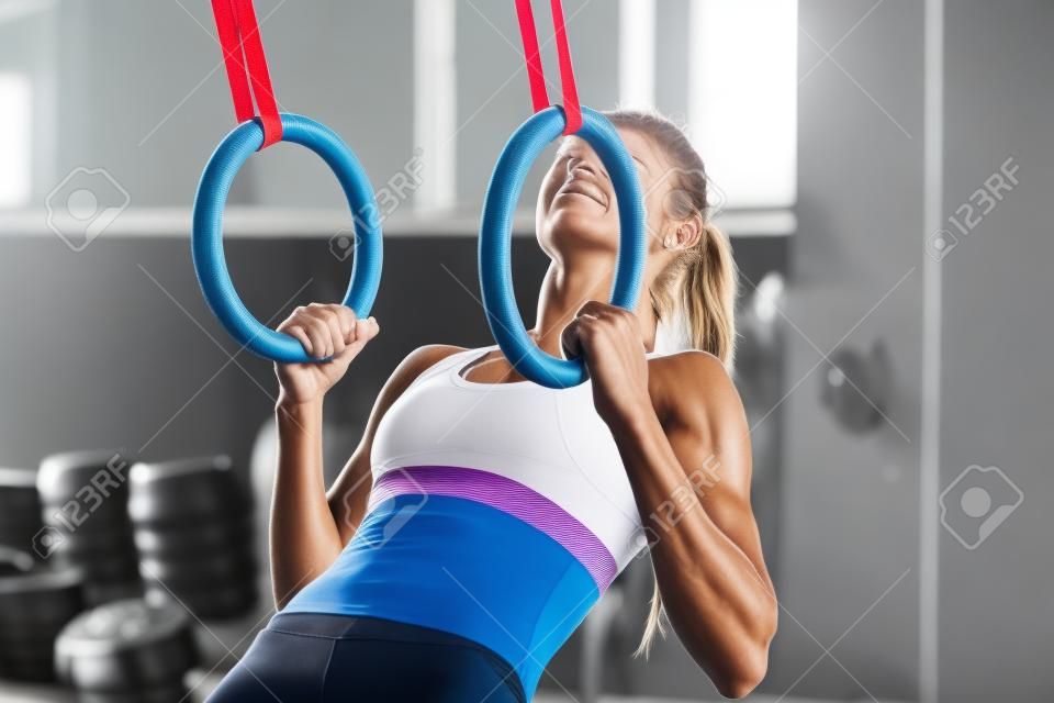 Determined woman exercising with gymnastic rings in gym stock