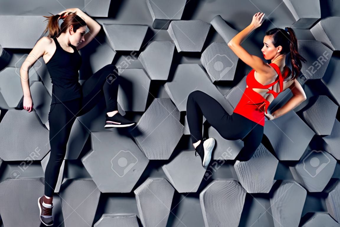 Fit women posing like a climber hanging on decorative wall