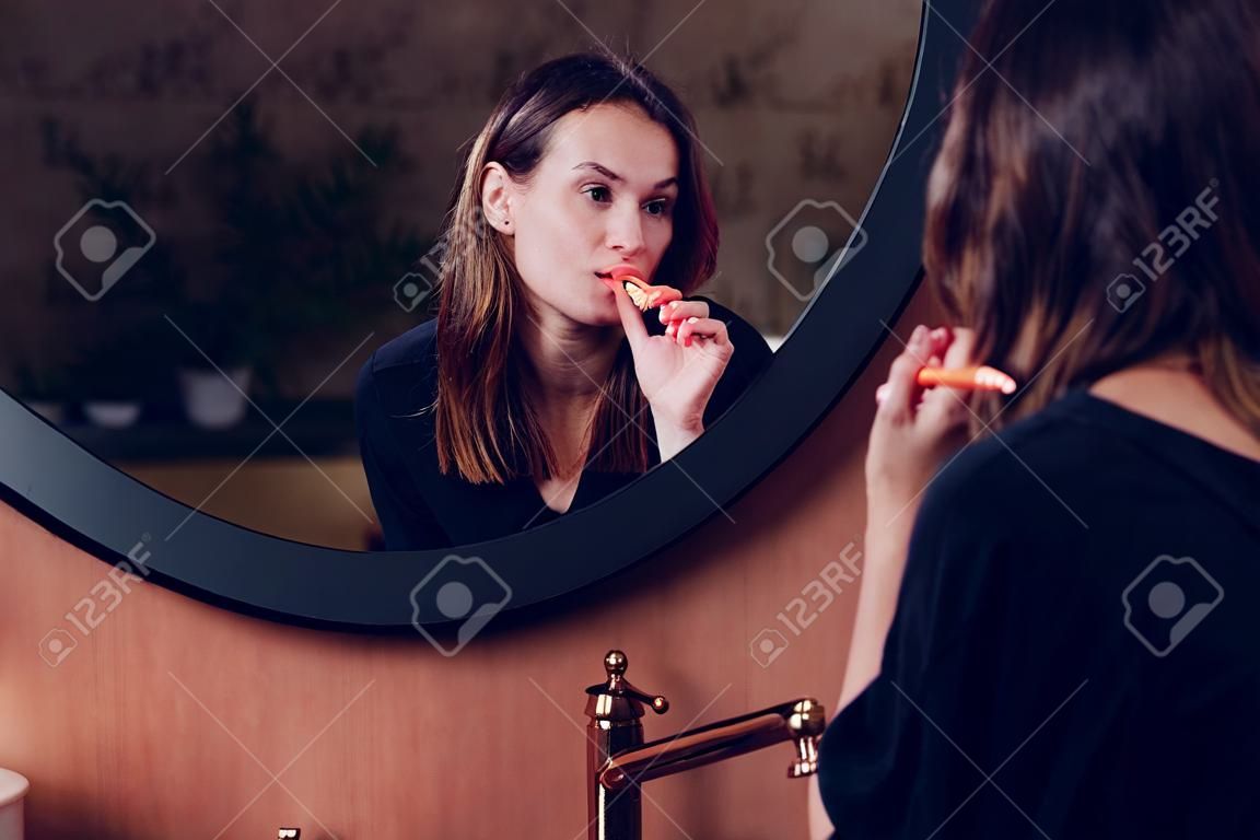 La mujer joven se cepilla los dientes antes de irse a dormir