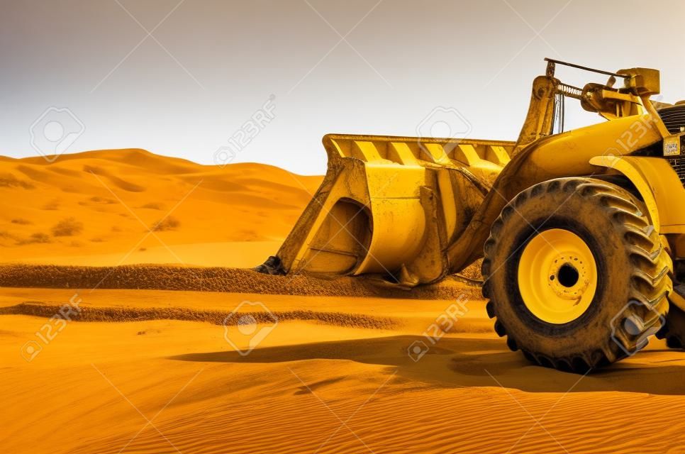 tractor amarillo con un cubo grande en el desierto