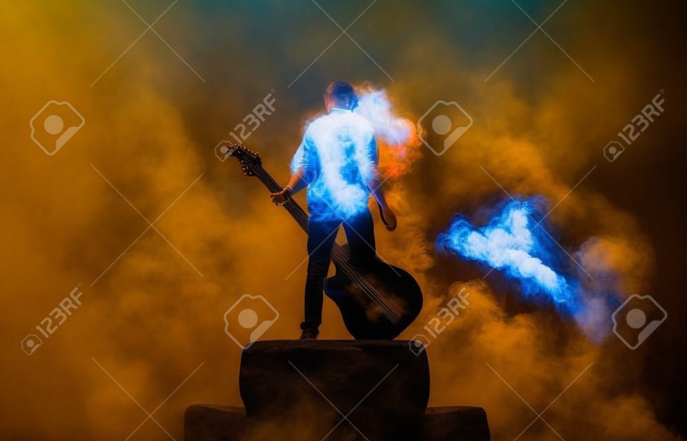 A zenész játszik egy nagy szikla gitár egy nagy füst