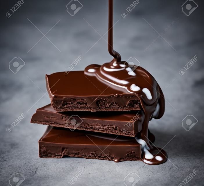 chocolat fondu est versé sur une pile de lait et de chocolat noir