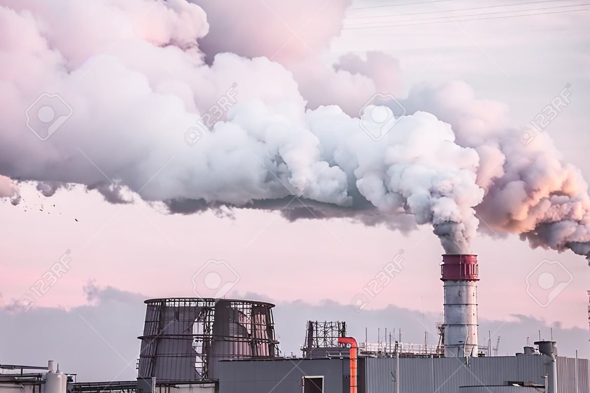 industrial chimneys with heavy smoke causing air pollution as an ecological problem on the pink sunset sky background