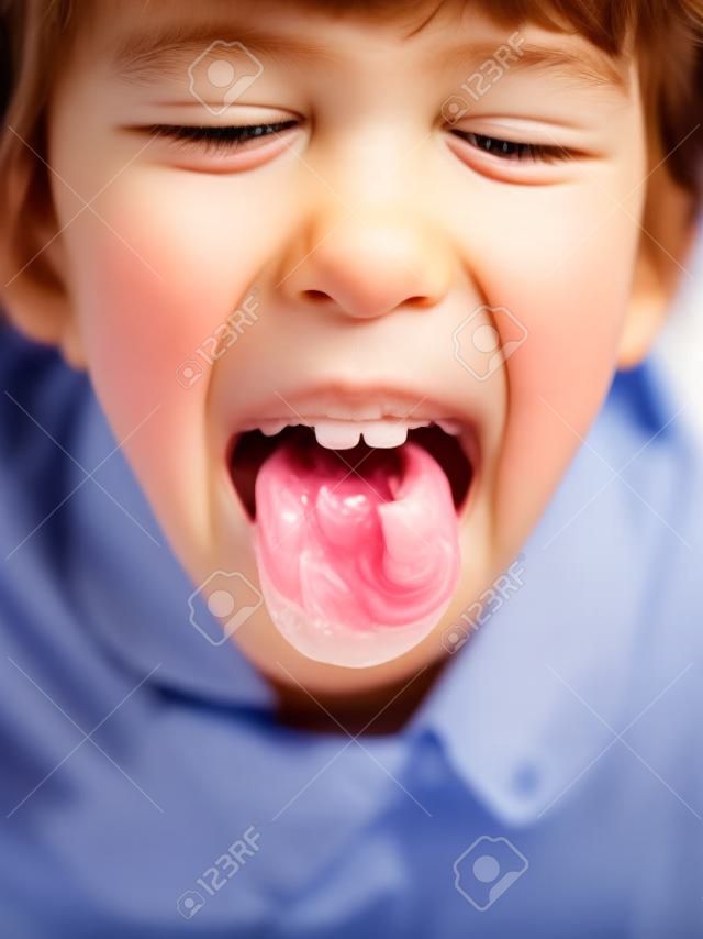 医者は子供の喉を調べます。少女は喉の痛みを示すために口を大きく開いた