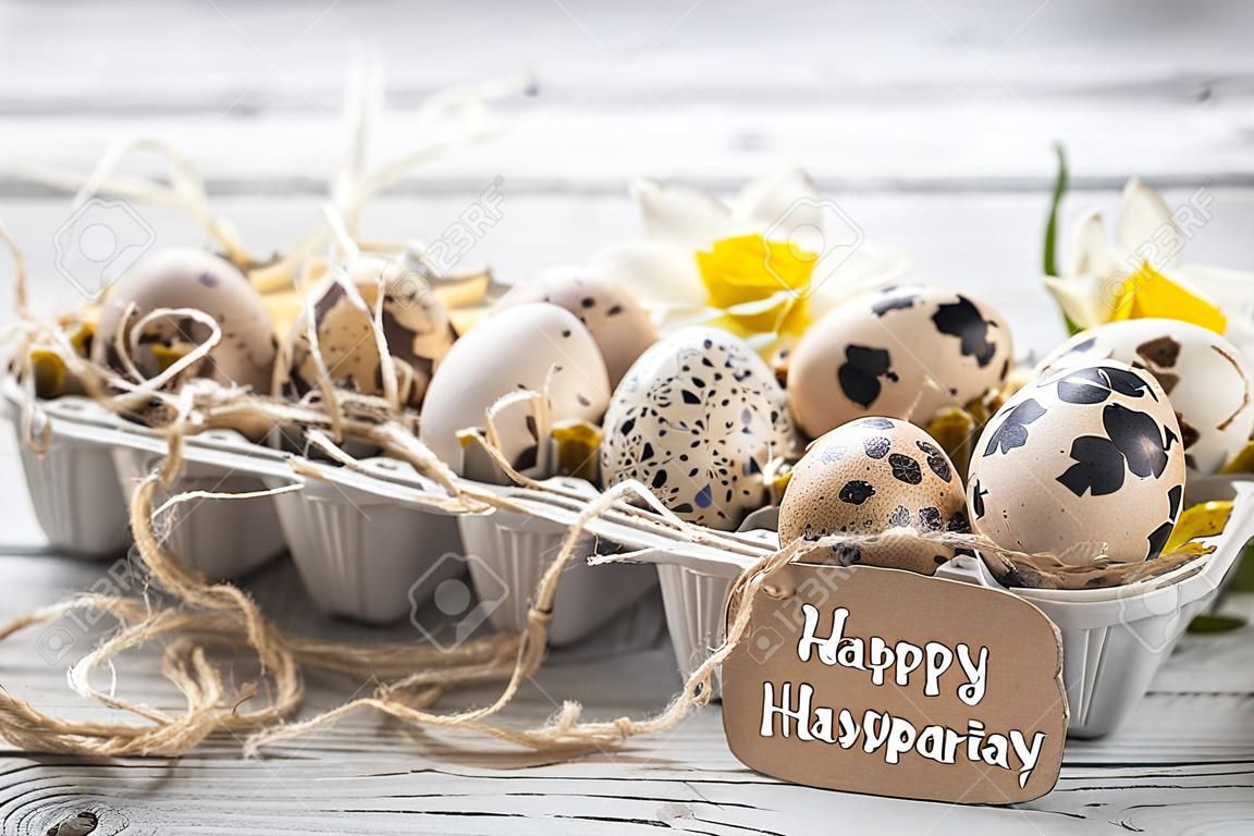 Easter eggs with flowers on a light wooden background with a congratulatory card ,concept holidays
