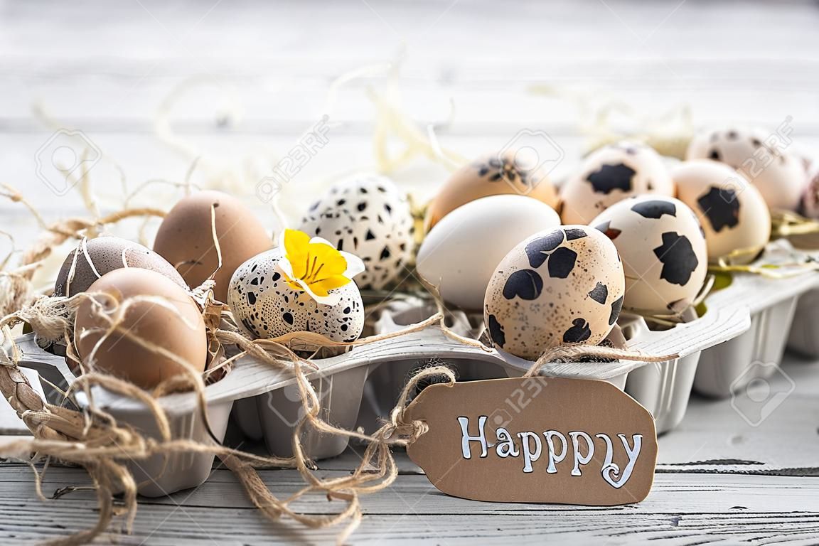 Uova di Pasqua con i fiori su un fondo di legno leggero con una carta di congratulazioni, feste di concetto