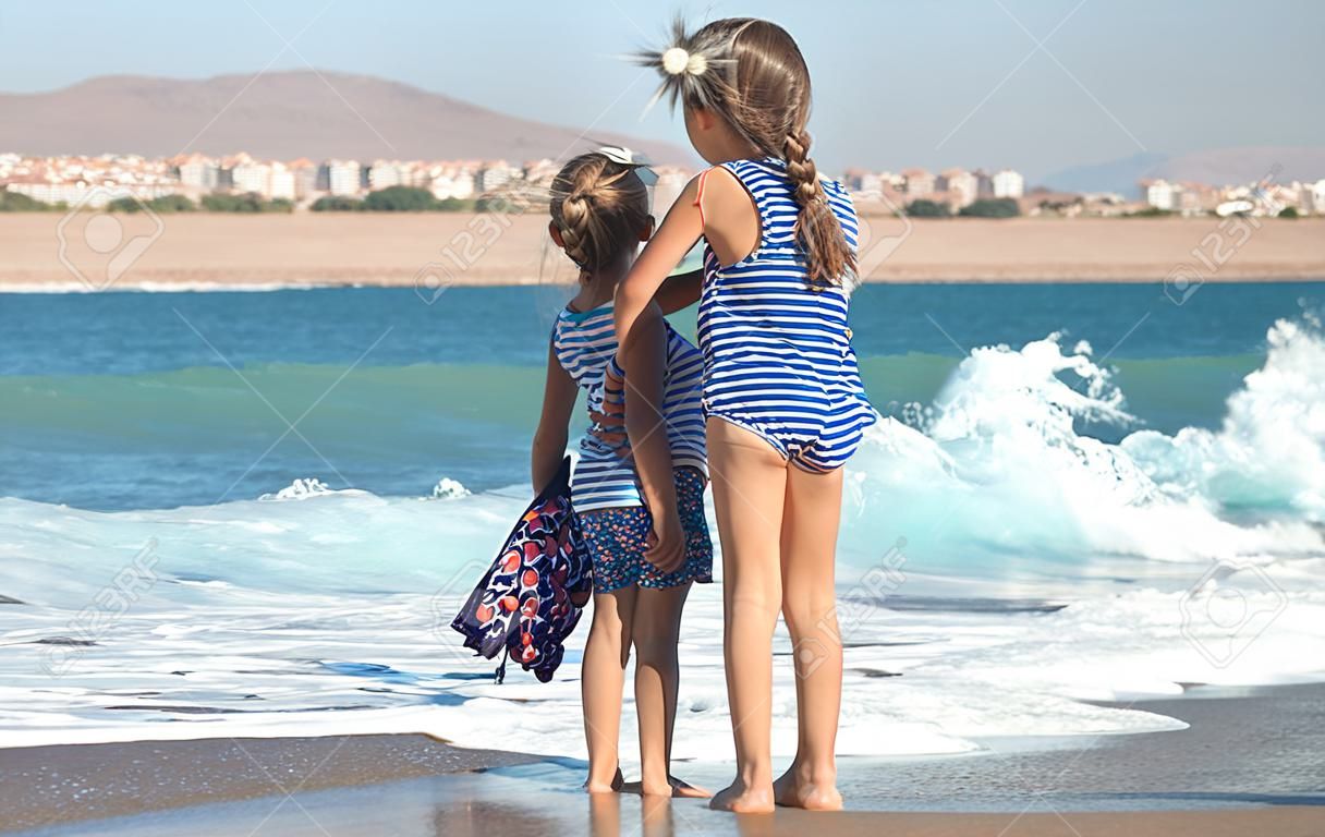 Dwie małe dziewczynki bawią się wzdłuż plaży nad morzem. pojęcie przyjaźni i rekreacji.