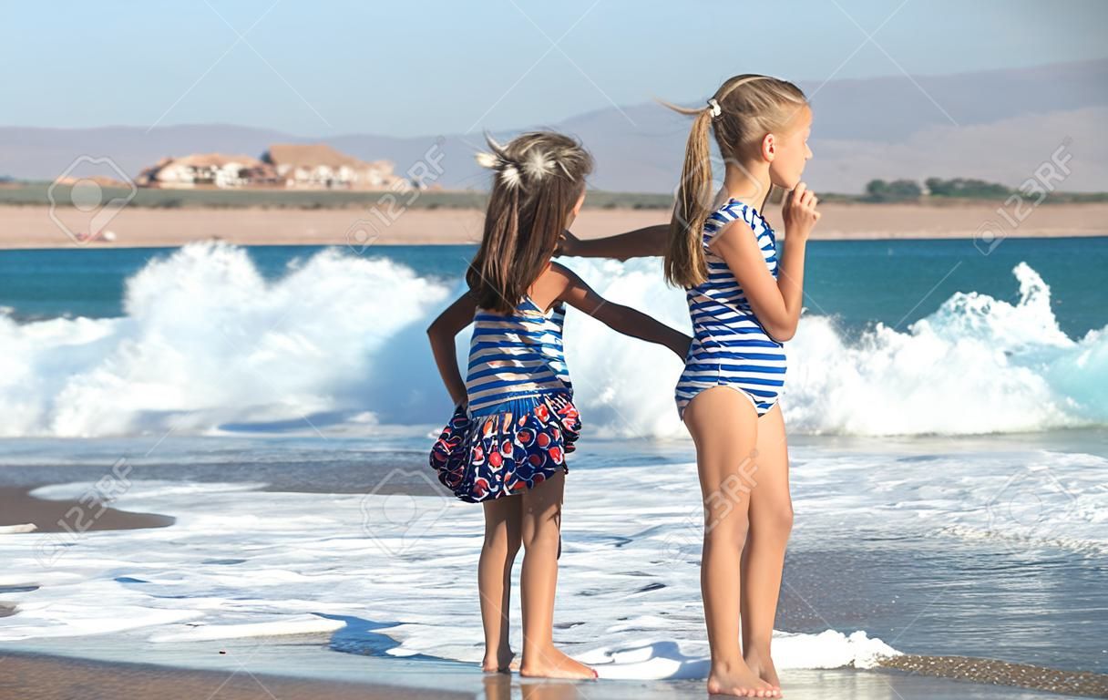 Dwie małe dziewczynki bawią się wzdłuż plaży nad morzem. pojęcie przyjaźni i rekreacji.