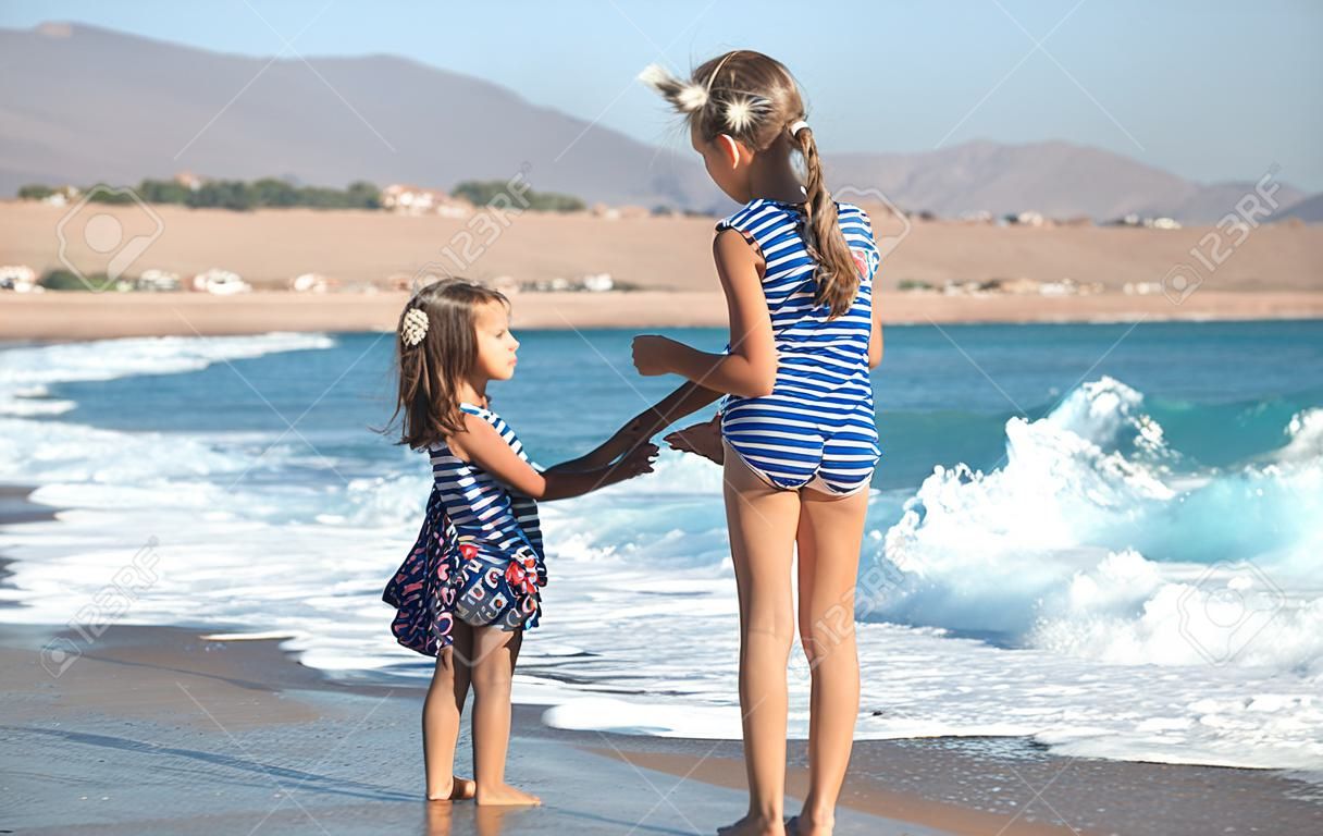 Deux petites filles jouent le long de la plage au bord de la mer. Le concept d'amitié et de loisirs.