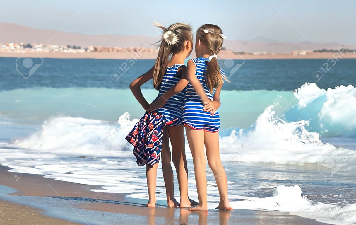 Due bambine giocano lungo la spiaggia in riva al mare. Il concetto di amicizia e ricreazione.