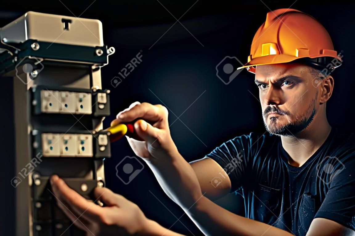 Ein Elektriker arbeitet in einer Schalttafel mit einem elektrischen Verbindungskabel.