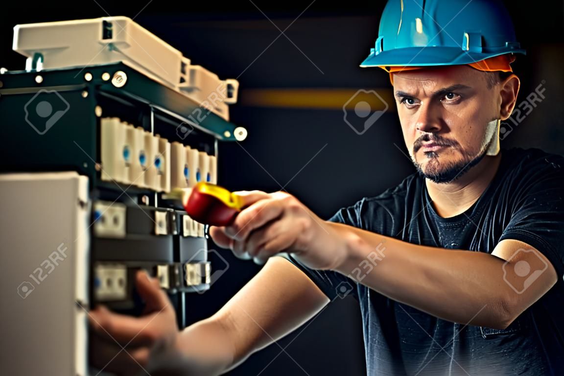 Elektryk płci męskiej pracuje w tablicy rozdzielczej z elektrycznym kablem połączeniowym.